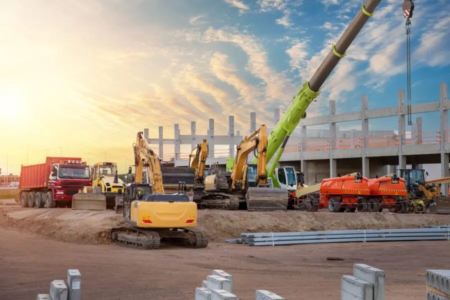 Large construction site with multiple excavators, a mobile crane, and trucks working on a multi-story building — the type of complex, multi-contractor project a wrap-up insurance program may cover.