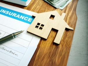 House model on an insurance policy document next to a pen