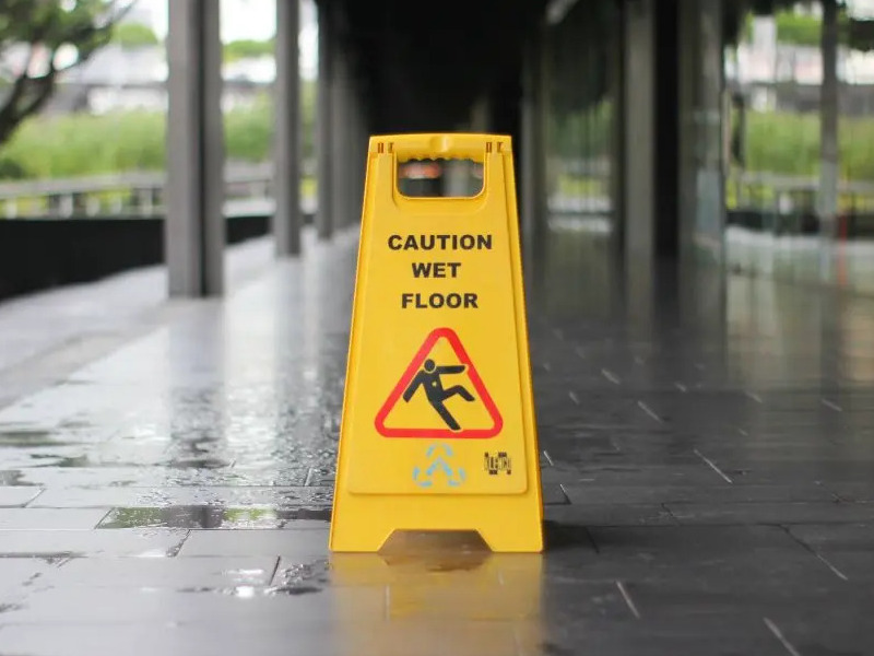 Yellow "Caution Wet Floor" sign on a wet walkway to prevent slips and falls