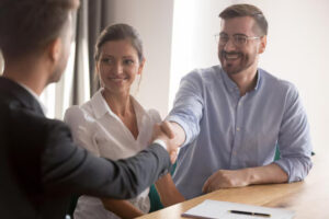 Insurance agent shaking hands with a couple during a policy meeting