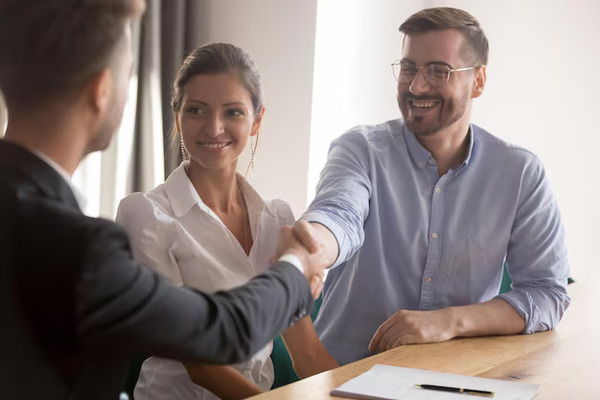 Insurance agent shaking hands with a couple during a policy meeting