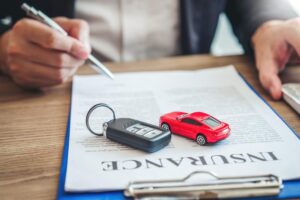 Car key and model car on auto insurance policy documents