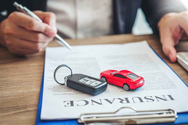 Car key and model car on auto insurance policy documents
