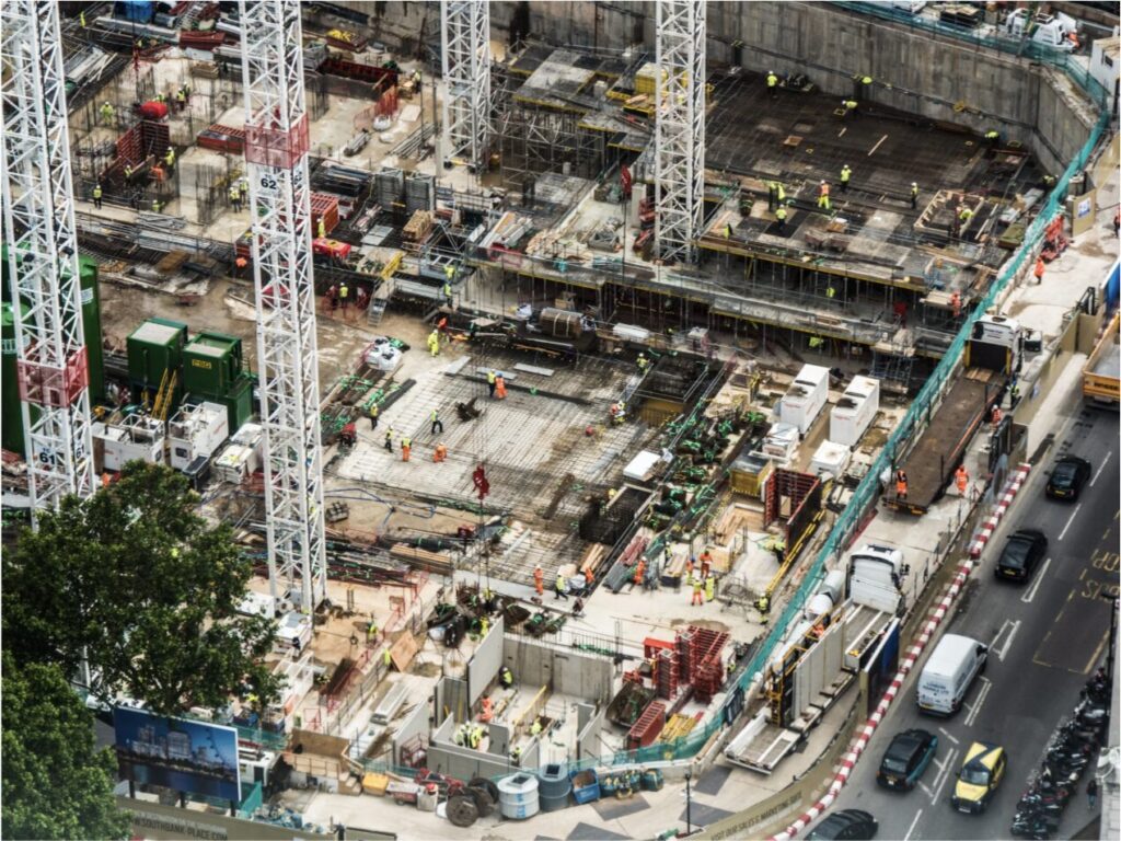 Aerial view of a large, active construction site with multiple trades working, representing the complexity of tracking subcontractor certificates of insurance.