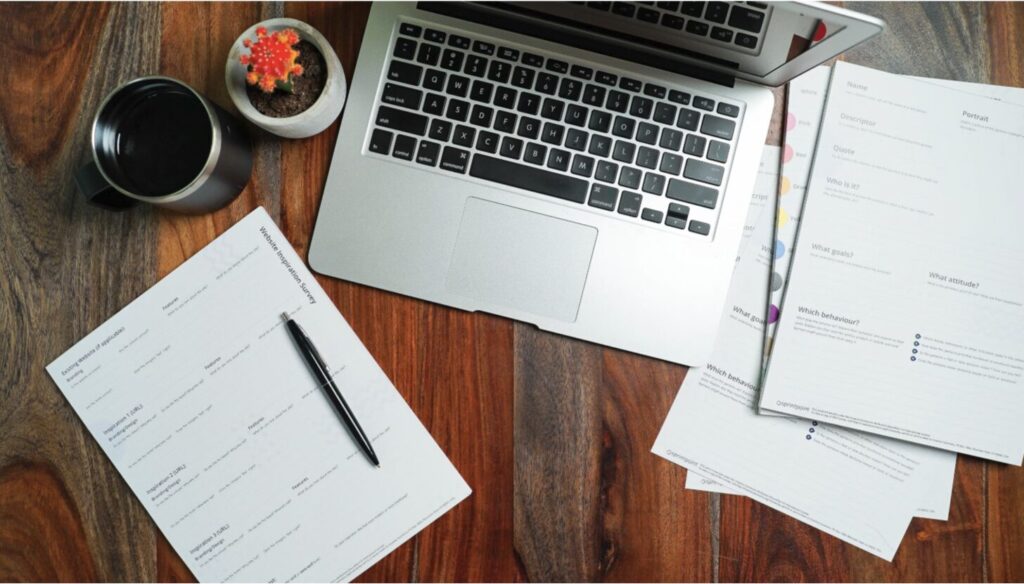 Laptop and paperwork organized on a desk, representing a certificate of insurance tracking system.