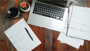 Laptop and paperwork organized on a desk, representing a certificate of insurance tracking system.