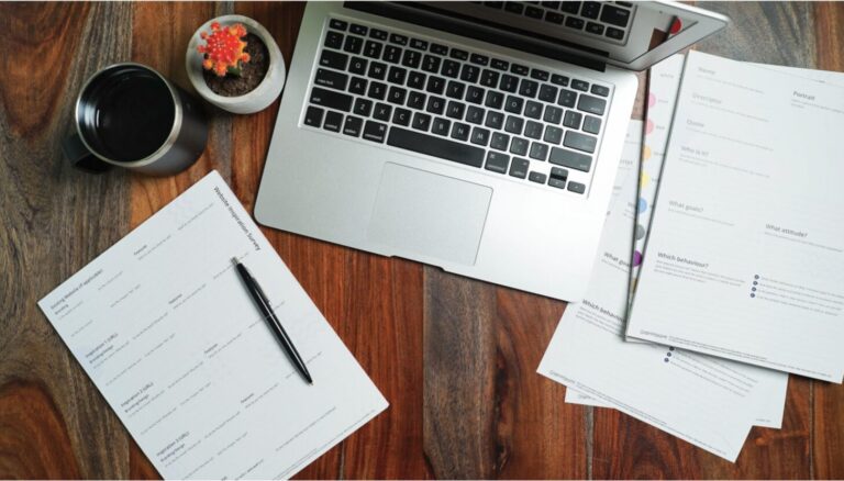 Laptop and paperwork organized on a desk, representing a certificate of insurance tracking system.
